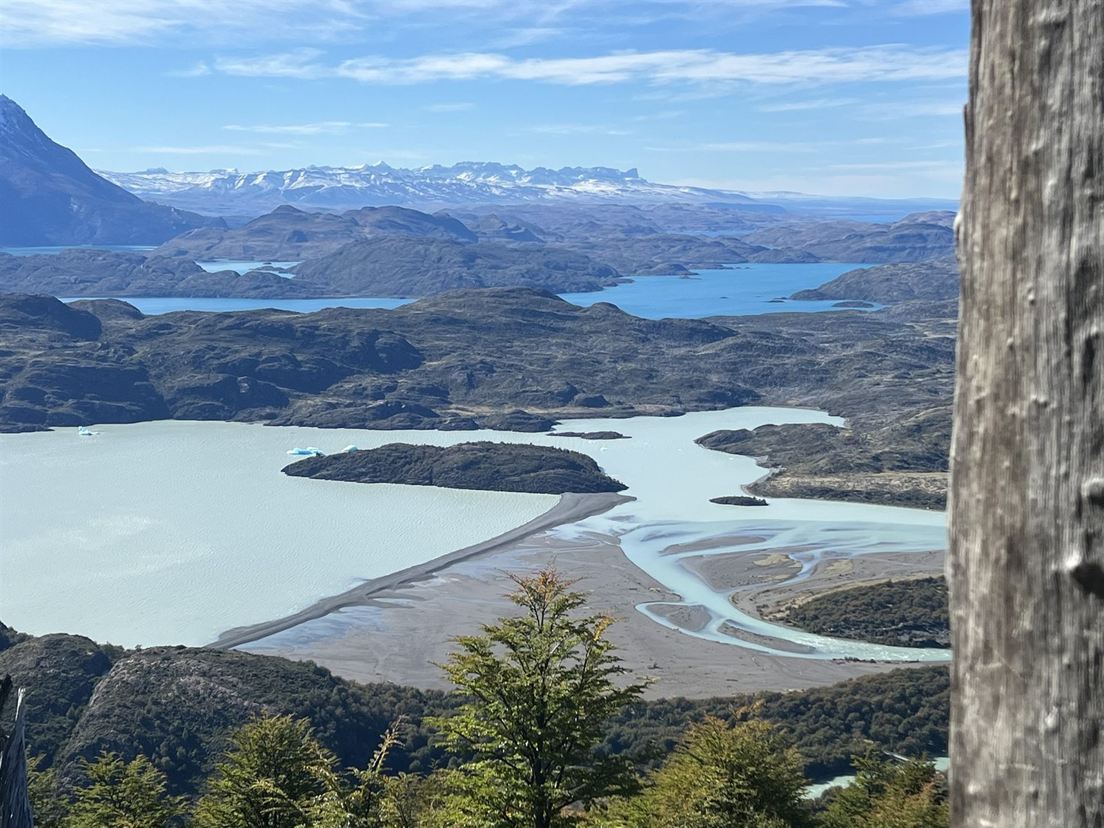 Aerial view of a turquoise river delta winding through Patagonian fjords toward distant mountains