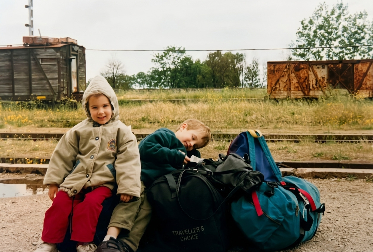 Nacho and his little sister sitting on suitcases at a train station