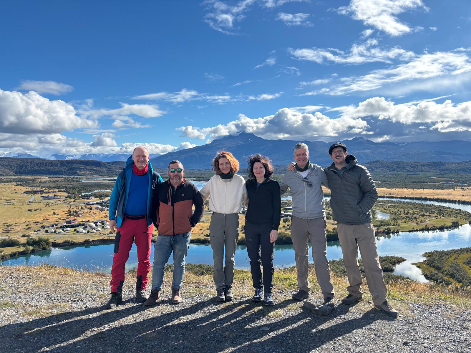Nacho and the Bruma Travel team on a hilltop overlooking a winding river, mountains in the distance
